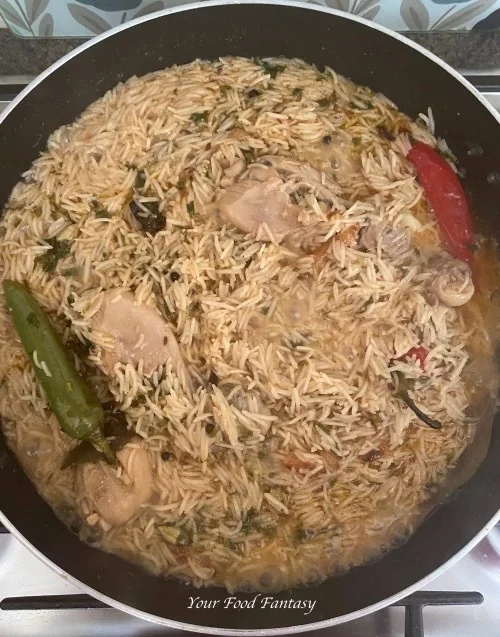 Cooking rice and chicken to make Yakhni Pulao